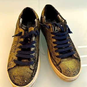 Gold and black low top sneakers.